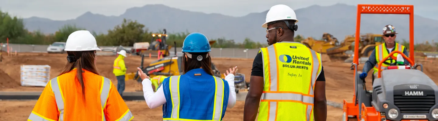 3 people on jobsite walking toward equipment