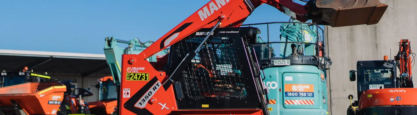 Man operating a wheel loader moving dirt at a construction site with safety barriers visible in the background.