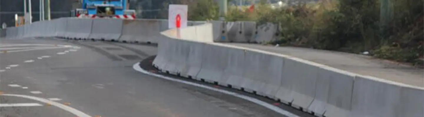 Long safety barriers lining a roadway construction zone to protect workers and guide traffic flow.