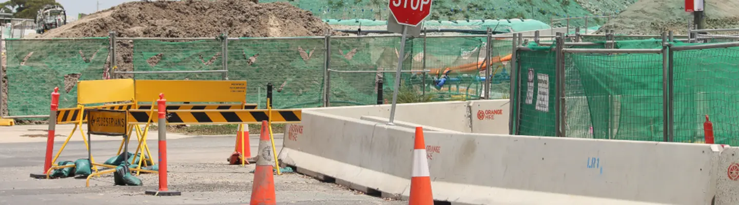 Different types of safety barriers placed along a road construction zone to manage traffic and protect workers.