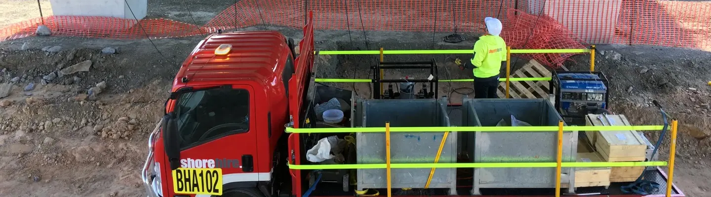  Worker on truck under bridge guiding ropes lifting structure with hydraulic jack during construction setup.