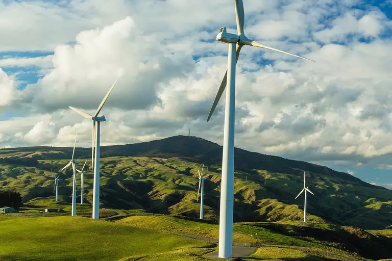 Windmills in a green, hilly space.