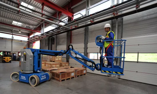 Worker on electric boom lift inside a warehouse