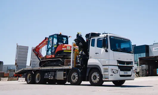 A truck transporting heavy construction equipment, emphasizing logistics and safety at work zones.