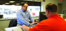 man at computer behind desk with another man