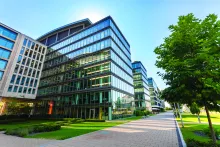 stock image of the outside of a glass office building near trees under a blue sky