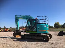 Construction equipment positioned at a roadside site, used for installing or maintaining safety barriers.