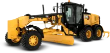 Grader truck leveling soil on a construction site, with safety barriers and other heavy equipment in the background.