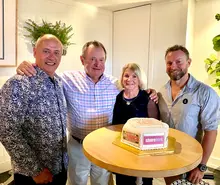 Company executives celebrating project success in the office with a cake, after safe construction completion.
