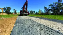 Max track vehicle positioned on a track mat, providing stable ground access at a construction site with safety measures in place.