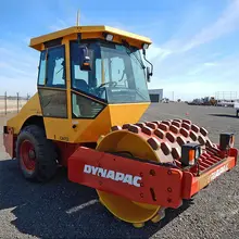 Picture of a roller machine on a construction site, surrounded by safety barriers and signage for hazard prevention.