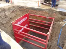 Workers installing internal props inside a shoring box placed in a trench to reinforce excavation walls and maintain safety.