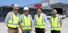Group of workers standing in front of a newly completed office building with safety barriers in place.