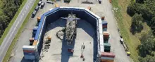 Ship surrounded by stacked shipping containers painted blue, creating a temporary blue screen setup for filming or visual effects work.